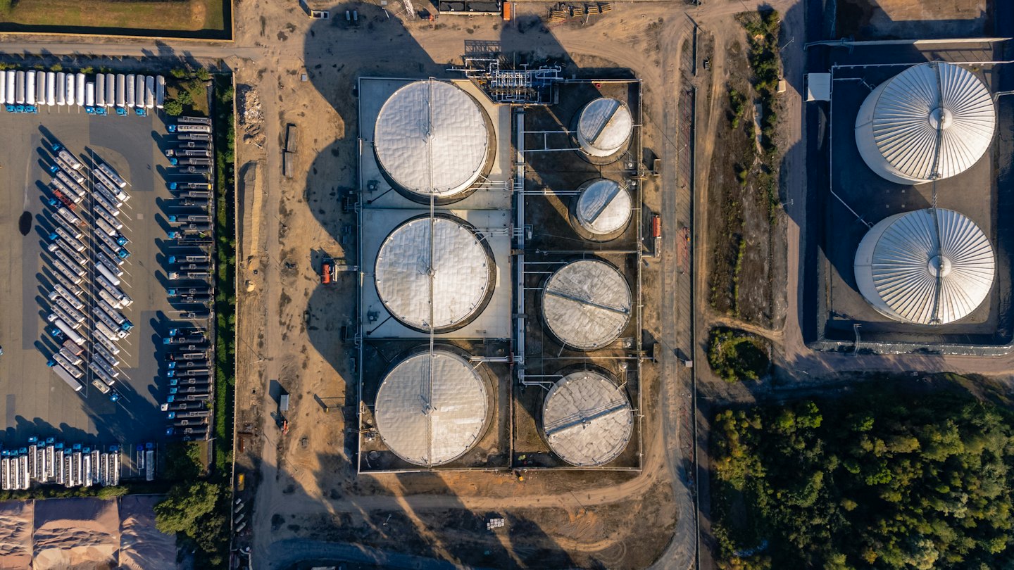 Endüstriyel bir alanda büyük gümüş depolama tankları ve kamyonlar.